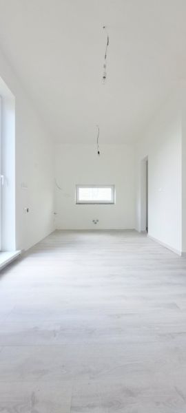 A room in a family house with white walls and a wooden decor floor.