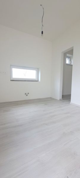 A room in a family house with a wooden decor floor and a small window.