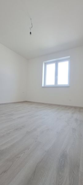 A room with a window and a wooden decor floor in a family house.
