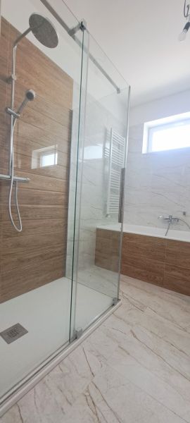 A bathroom with a modern shower enclosure and a bathtub in a family house.