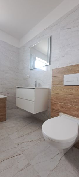 A bathroom in a family house with a sink, mirror, and floor with a wooden decor.