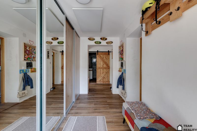 A hallway in a family house with a mirrored wardrobe and a floor with a wooden decor.