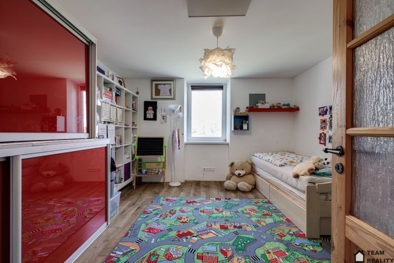 Children's room in a family house with a colorful carpet and a wooden decor floor.