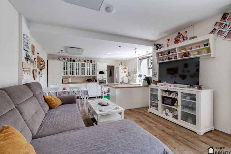 Living room in a family house with wood-patterned flooring, white furniture, and a sofa.