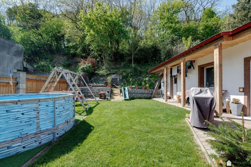 The garden of a family house in Potzneusiedl with a swimming pool, lawn, and wooden swing.