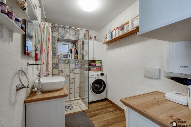 A bathroom in a family house with wooden floor decor and a shower.