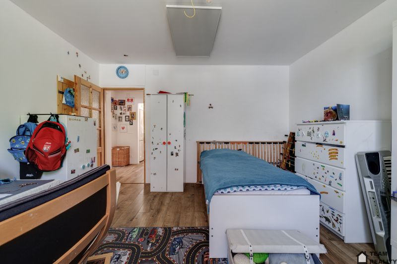 Children's room with a bed, shelves, and a wooden floor decor in a family house.