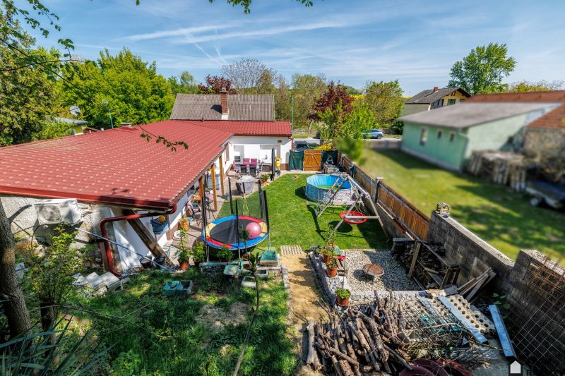A family house in Potzneusiedl with a yard, trampoline, swimming pool, swing, and garden furniture.