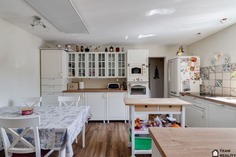 A kitchen in a family house with white furniture and a wooden decor floor.