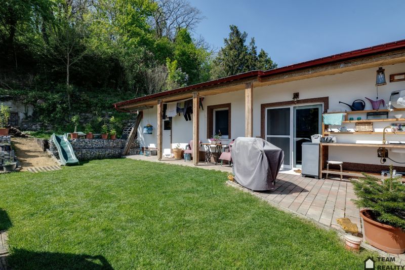 A family house in Potzneusiedl with a terrace, greenery, and a children's slide, surrounded by nature.
