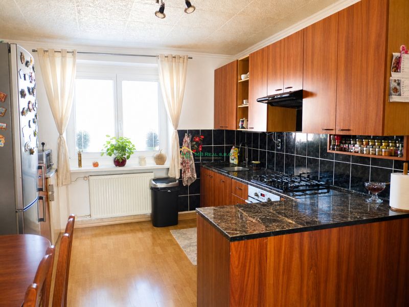 A kitchen in a 2-room apartment with a wooden decor floor and dark tiles.
