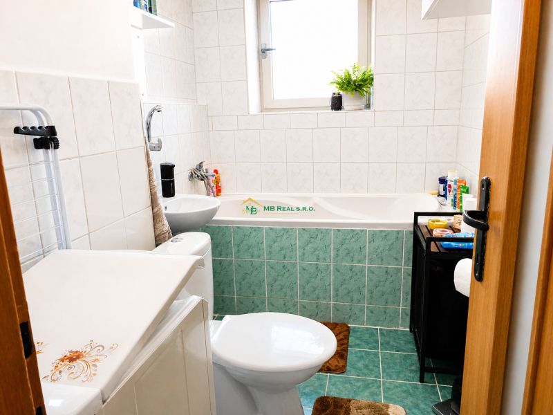 A bathroom with a bathtub and a sink in a 2-room apartment, tiled walls.