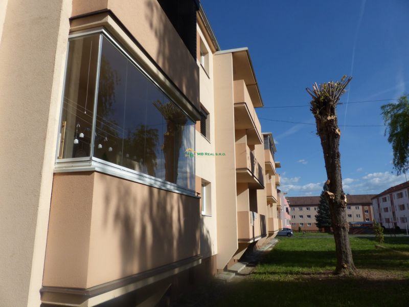 An apartment building with balconies and trimmed trees in Žiar nad Hronom, suitable for a 2-room apartment.