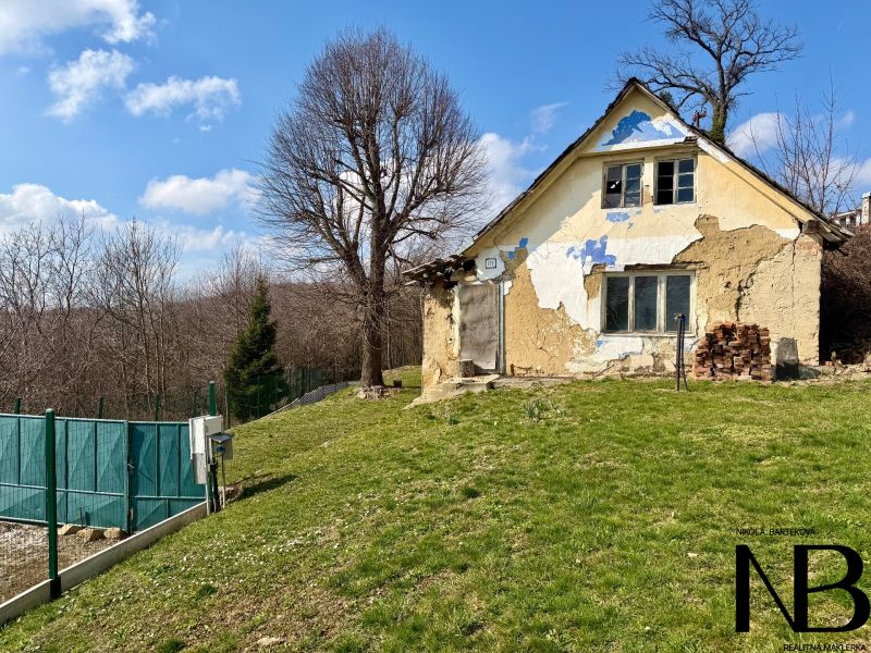An older house on a plot in Lubina surrounded by nature and trees.