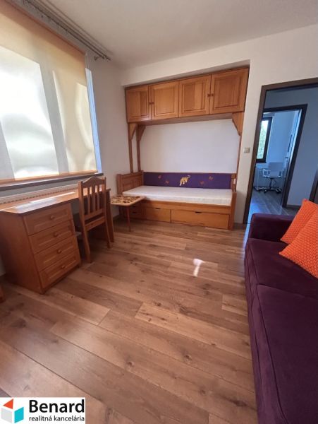 A room in a 3-room apartment with wooden decor, cabinets, and a couch.