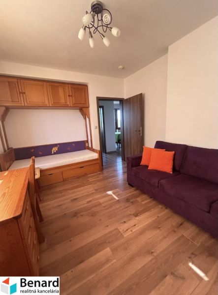 A room in a 3-room apartment with a wooden decor floor and a rainy view from the window.