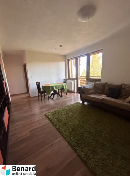 Living room of a 3-room apartment with a wooden decor floor, dining table, and sofa.