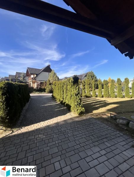 An airy exterior in Stará Lesná with a driveway surrounded by greenery and family houses.