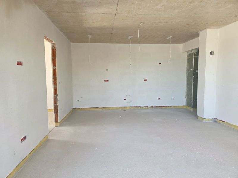 A room in a 3-room apartment with a concrete ceiling and bare walls.