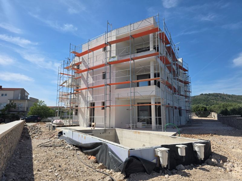 Construction of a 3-room apartment in Tribunj with an in-ground pool and scaffolding.