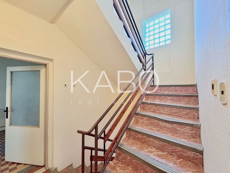 A staircase in a family house with a glass block window and open doors.