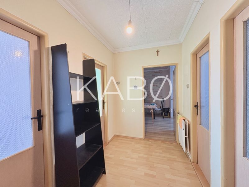 A hallway in a family house with a wooden decor floor and a black shelf.