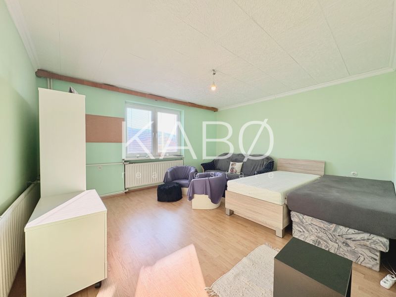 A room with beds, a sofa, and a wooden decor floor in a family house.