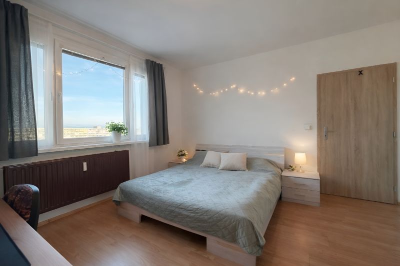 Bedroom in a 4-room apartment with a bed, curtains, and a wooden decor floor.