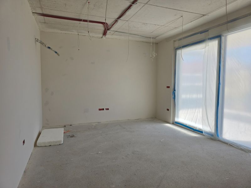 Unfinished interior of a 3-room apartment with a plastic window and raw flooring.
