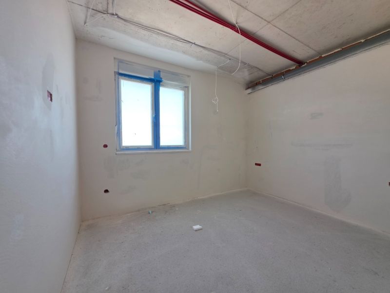 An empty room in a 3-room apartment with a concrete floor and a window.