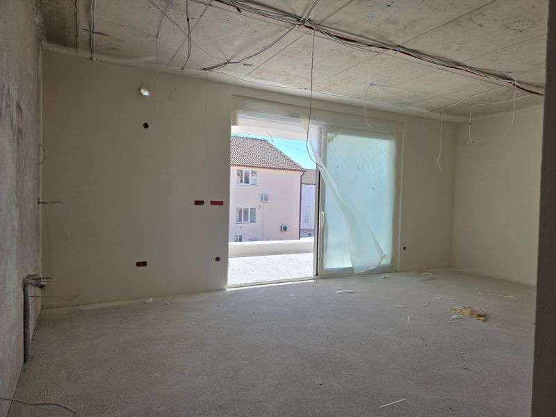 A vacant space in a 3-room apartment with an opening to the balcony and unfinished electrical installations.