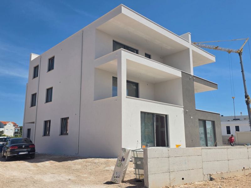 A newly built three-story apartment building in the town of Srima under a blue sky.