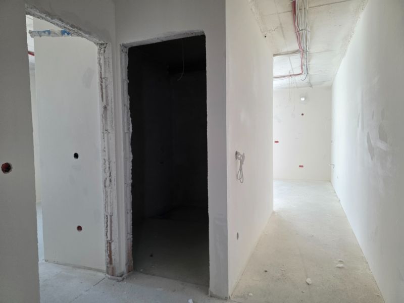 Unplastered walls and exposed electrical wiring in a 3-room apartment.