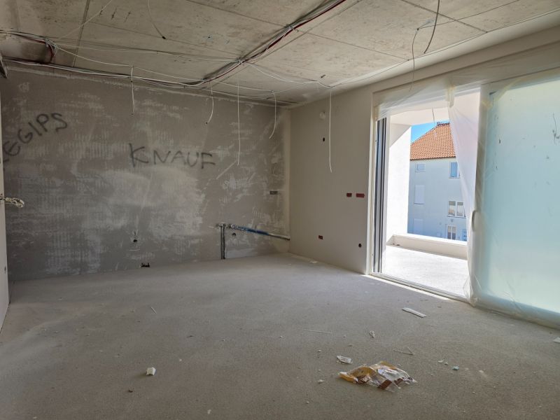 Under-construction 3-room apartment with a view of the terrace, unfinished walls, and electrical installation.