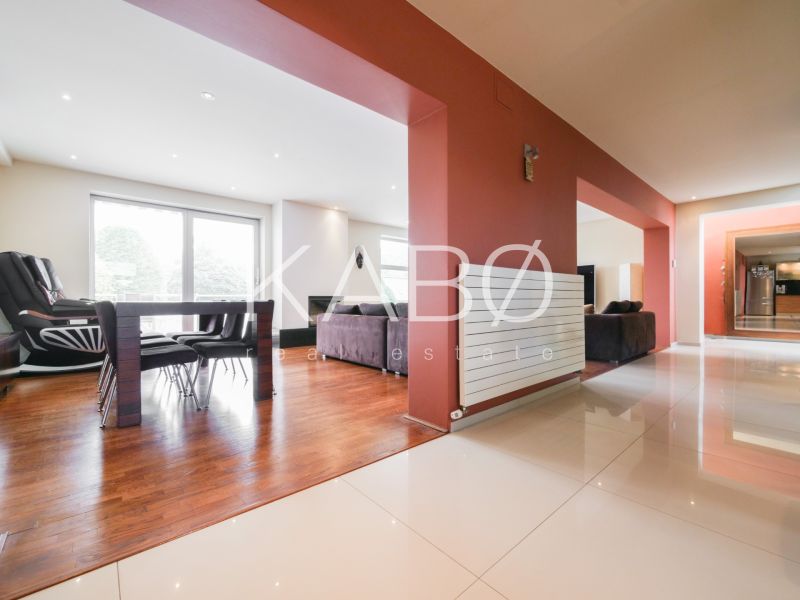Living room in a family house with wood-patterned flooring and a dining table.