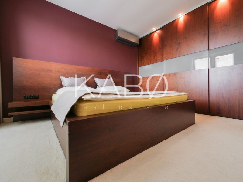 Bedroom in a family house with a bed, built-in wardrobe, and a burgundy wall.
