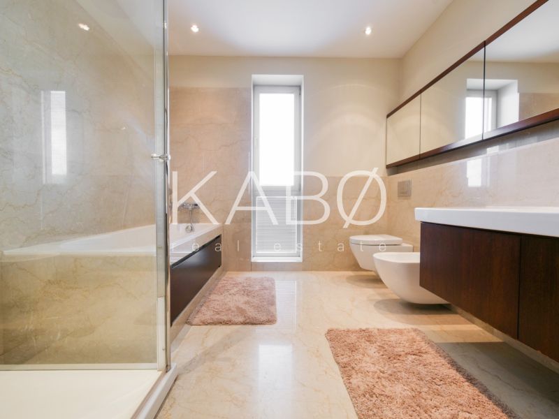 Bathroom in a family house with a bathtub, sink, and mirrored cabinets.