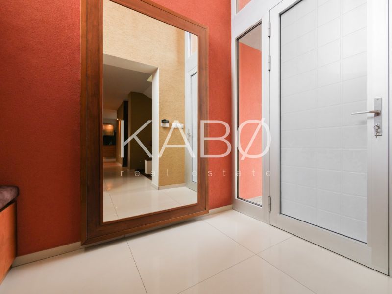 The interior of a family house with a large mirror, white doors, and beige tiles.