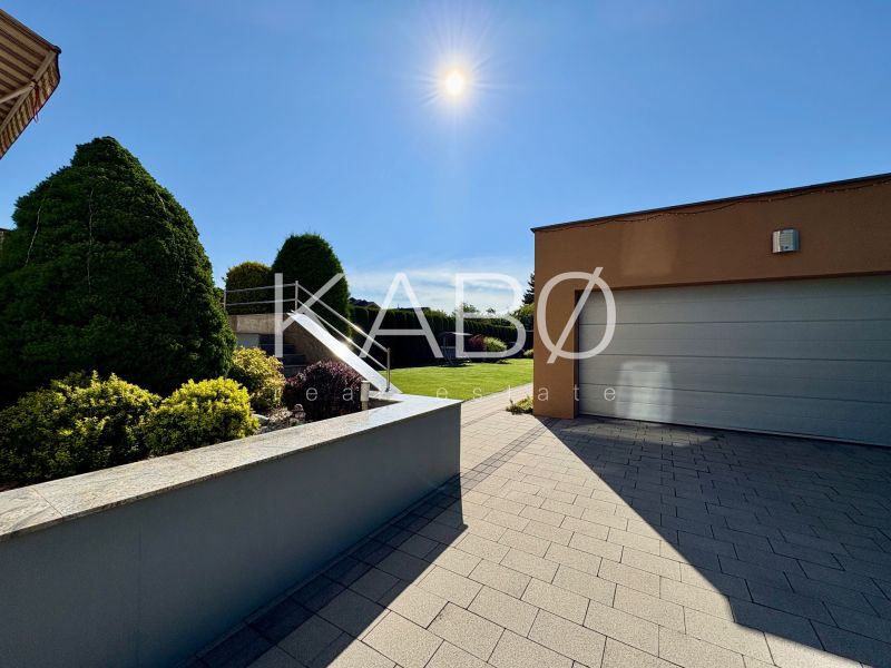 The exterior of a family house in Partizánske with a garden and a garage under sunny weather.