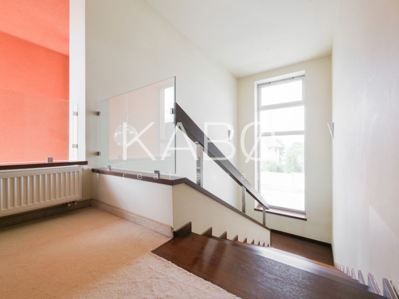 A staircase with modern railing and carpet in a family house, sunny room.