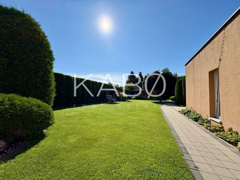 The garden of a family house in Partizánske with a well-maintained lawn and a paved walkway.