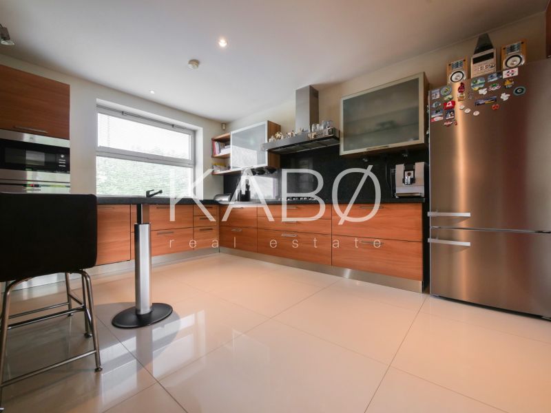 A kitchen in a family house with a chrome refrigerator and a wooden decor floor.