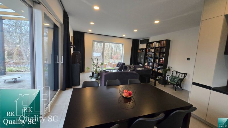 Living room in a family house with spacious windows and comfortable seating.