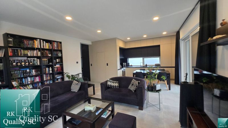 Living room with a library and kitchen in a family house, floor with wooden decor.