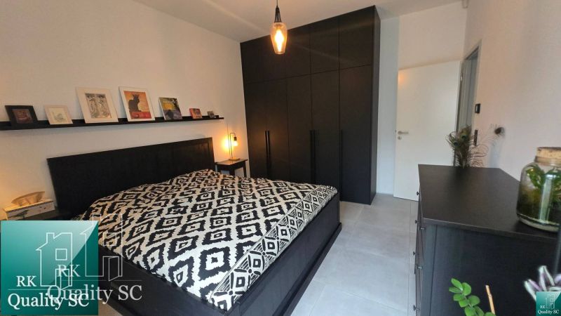 A bedroom with black furniture, artistic decorations, and a patterned bedspread.