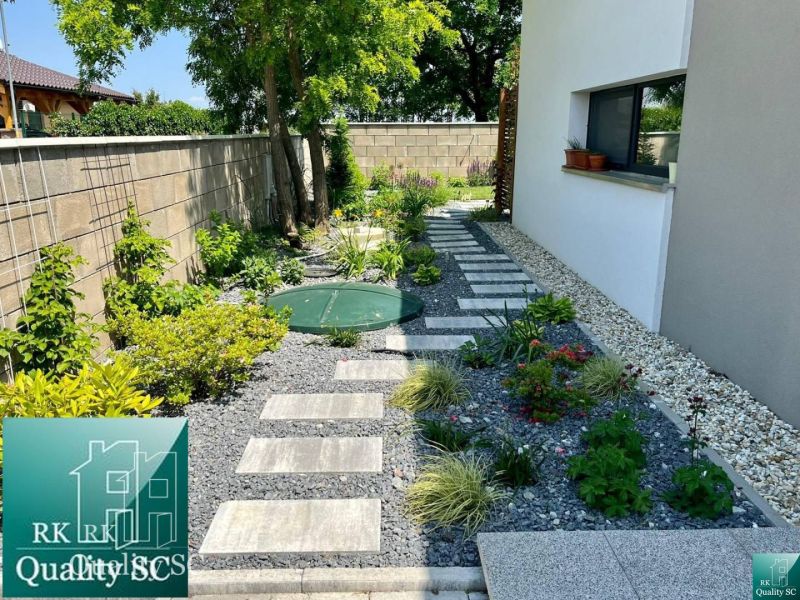 Garden path in a family house in Senec surrounded by plants and stones.