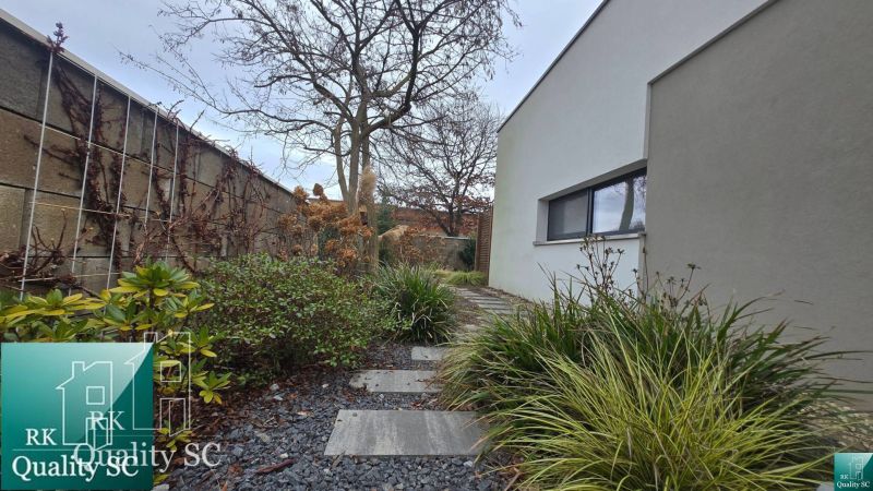 A family house in Senec with a landscaped garden path, decorated with pebbles and green plants.