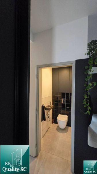 A toilet in a family house with black tiles and a light floor.