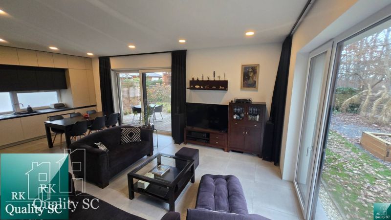 Living room in a family house with a sofa, dining table, and a view of the terrace.