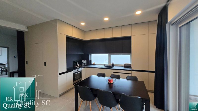 A kitchen in a family house with an elegant kitchen unit and a dining table with chairs.